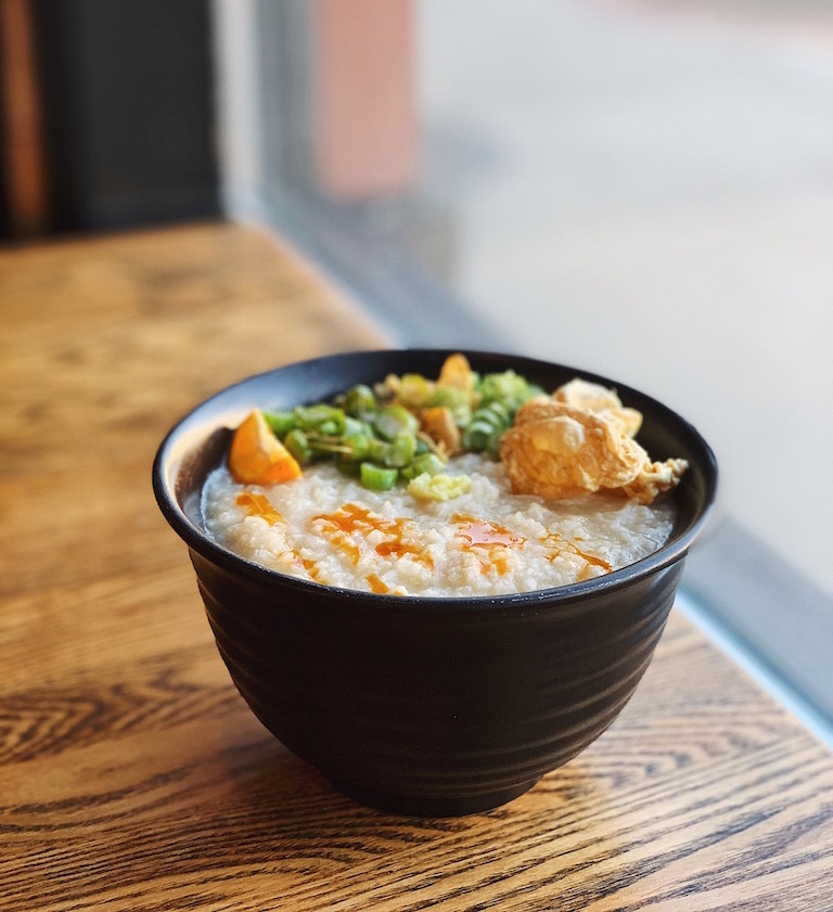 Irenia’s interpretation of arroz caldo is a bit more subdued. The toppings are simple and elegant. Sliced brassicas and green onion are neatly piled to one side with bits of fried garlic, fresh grated ginger, a wedge of calamansi, and dabs of chili oil. Chicken skin, similar to pork chicharrón, serves as a delicate garnish and has an acidic saltiness to it that I’ve decided I can eat by the fistful.